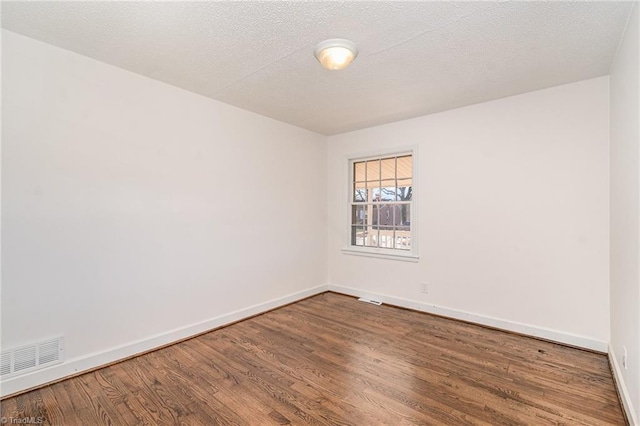 empty room with hardwood / wood-style floors and a textured ceiling