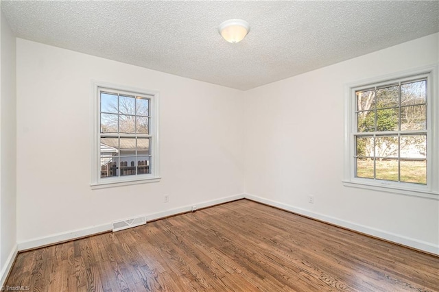 unfurnished room featuring hardwood / wood-style floors, a healthy amount of sunlight, and a textured ceiling