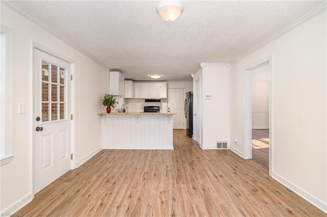 kitchen featuring kitchen peninsula, white cabinets, light hardwood / wood-style floors, and a textured ceiling