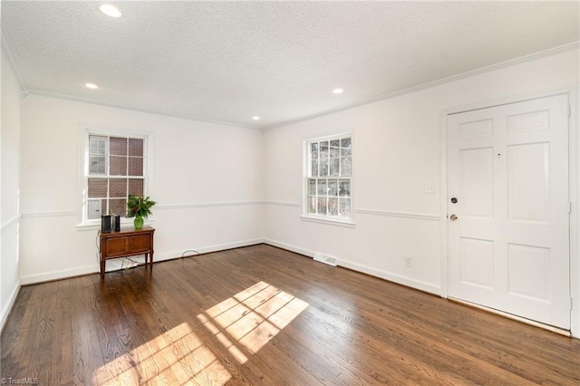 entrance foyer featuring dark hardwood / wood-style flooring, a textured ceiling, and ornamental molding