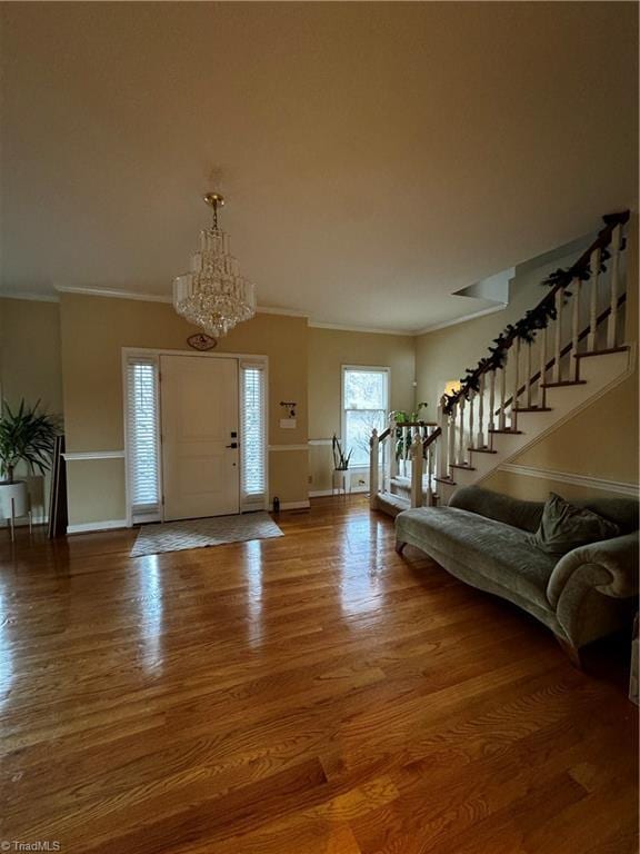 entrance foyer with ornamental molding, stairway, wood finished floors, and baseboards