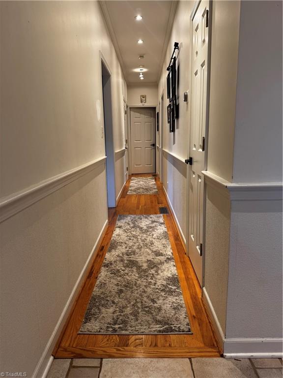 corridor with crown molding, baseboards, dark wood-style flooring, and recessed lighting