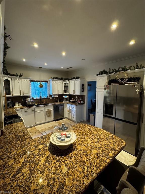 kitchen featuring white cabinets, dishwasher, a kitchen breakfast bar, stainless steel refrigerator with ice dispenser, and recessed lighting