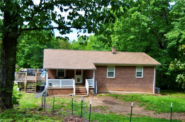 view of front of property featuring covered porch, a chimney, and brick siding