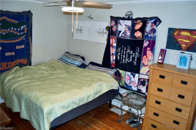 bedroom featuring crown molding, wood finished floors, and a ceiling fan