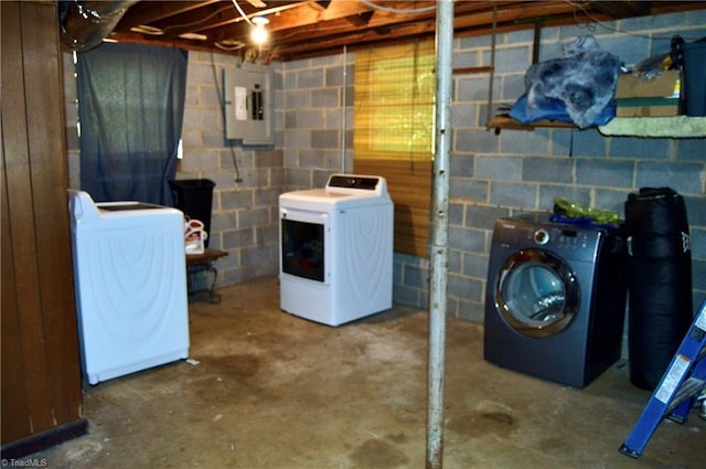 laundry area featuring washer and dryer, electric panel, and concrete block wall
