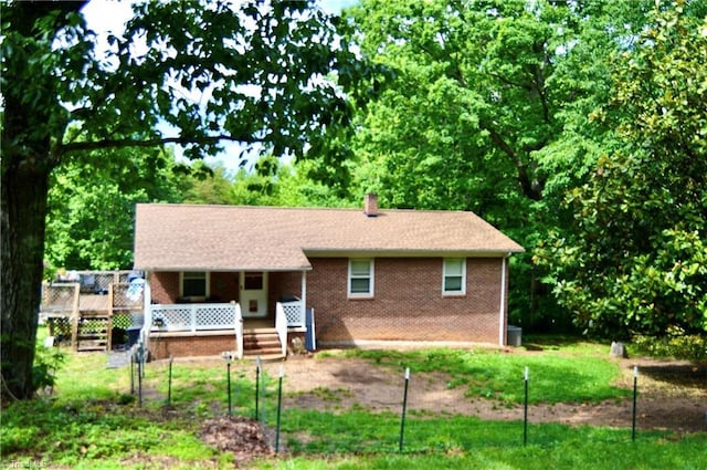 rear view of house featuring a chimney, a porch, and brick siding