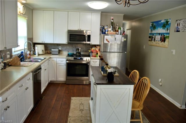 kitchen with appliances with stainless steel finishes, a sink, dark wood-style floors, backsplash, and ornamental molding