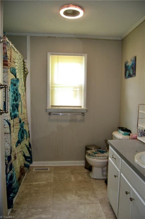 full bathroom with ornamental molding, toilet, vanity, and baseboards