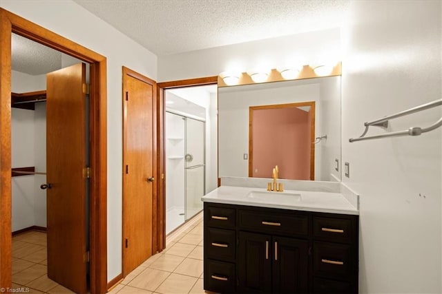 bathroom featuring vanity, tile patterned flooring, a textured ceiling, and an enclosed shower