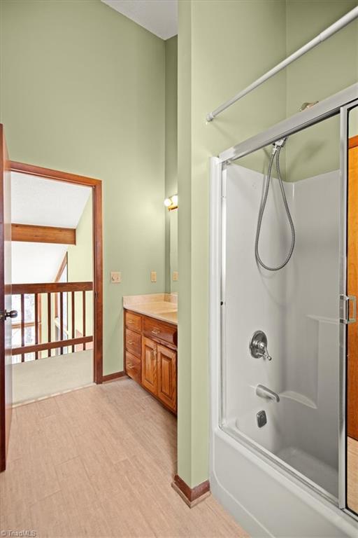 bathroom with wood-type flooring, bath / shower combo with glass door, and vanity