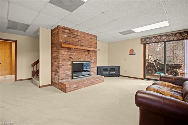 carpeted living room featuring a brick fireplace and a drop ceiling