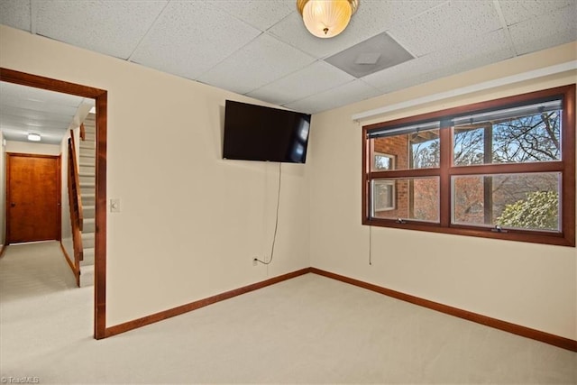 unfurnished room with a paneled ceiling and carpet flooring