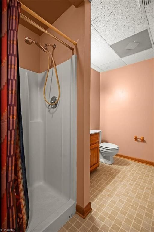 bathroom featuring toilet, a paneled ceiling, walk in shower, and vanity