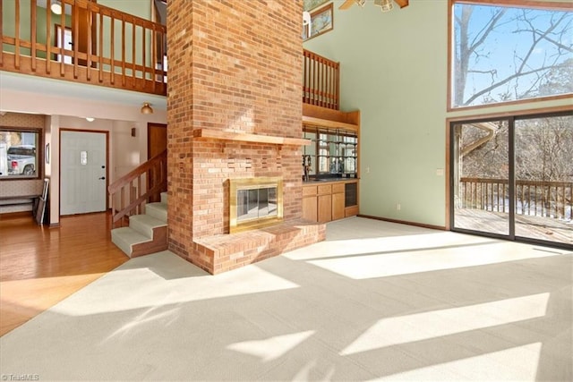 living room with a brick fireplace, a high ceiling, and light colored carpet