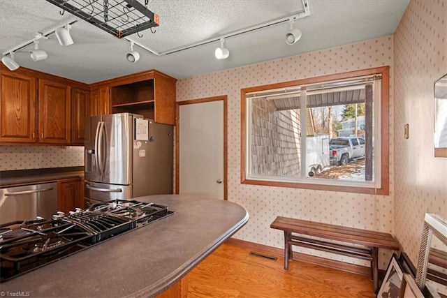 kitchen featuring appliances with stainless steel finishes, track lighting, and light wood-type flooring