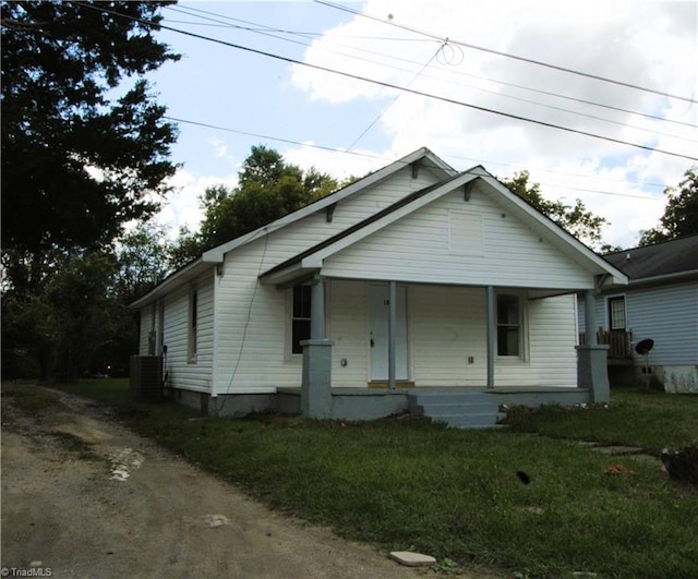 bungalow with a porch, a front lawn, and central AC unit