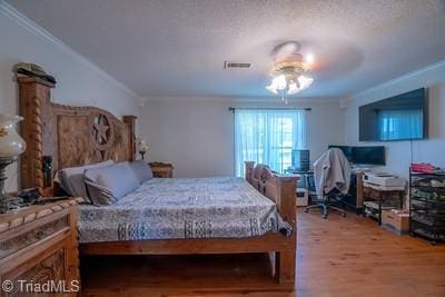 bedroom with hardwood / wood-style flooring, ceiling fan, ornamental molding, and a textured ceiling