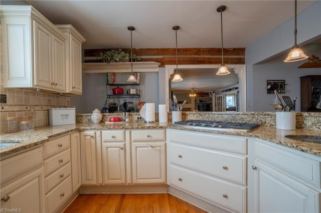 kitchen with kitchen peninsula, light stone counters, light wood-type flooring, and hanging light fixtures