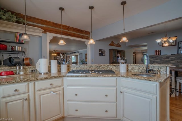 kitchen with sink, stainless steel gas cooktop, pendant lighting, white cabinets, and light wood-type flooring