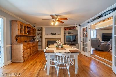 dining area with french doors, light hardwood / wood-style flooring, ceiling fan, and crown molding