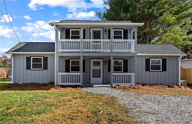 front facade with covered porch, a balcony, a front lawn, and cooling unit