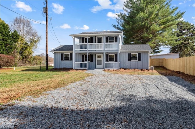 front of property with covered porch, a balcony, and a front yard