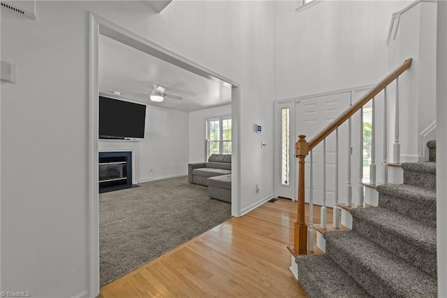 carpeted foyer featuring ceiling fan and a high ceiling