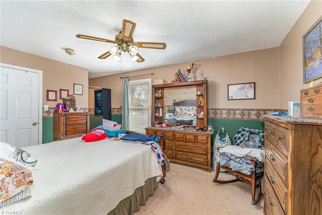 bedroom with light colored carpet, a textured ceiling, and a ceiling fan