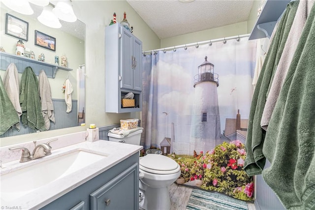 bathroom with toilet, a textured ceiling, wood finished floors, a shower with shower curtain, and vanity