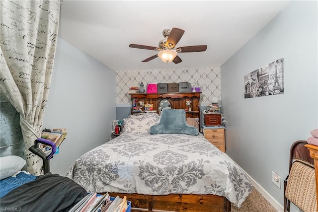 carpeted bedroom featuring wallpapered walls, an accent wall, baseboards, and a ceiling fan