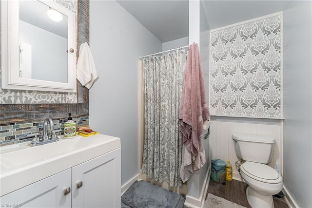 bathroom with toilet, backsplash, wood finished floors, baseboards, and vanity