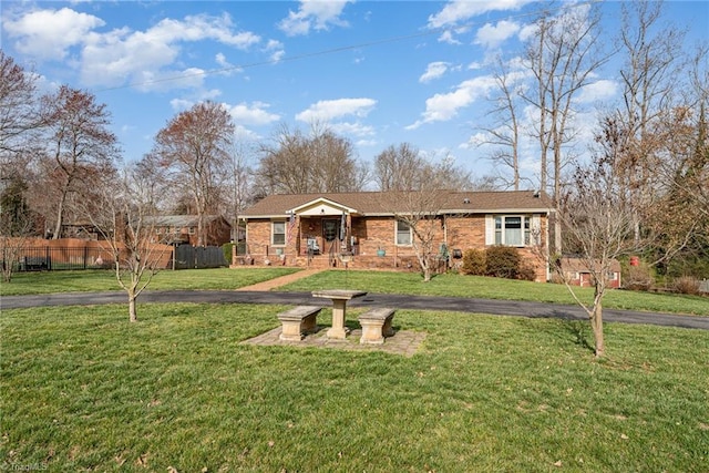 ranch-style house featuring driveway, brick siding, a front lawn, and fence