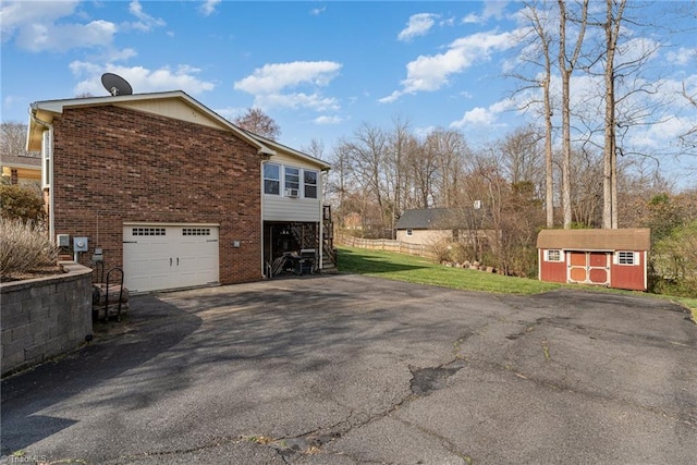 view of side of property featuring a storage shed, an attached garage, brick siding, and driveway