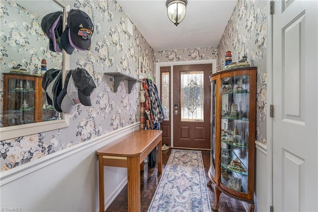 entrance foyer featuring a wainscoted wall, a textured ceiling, wood finished floors, and wallpapered walls