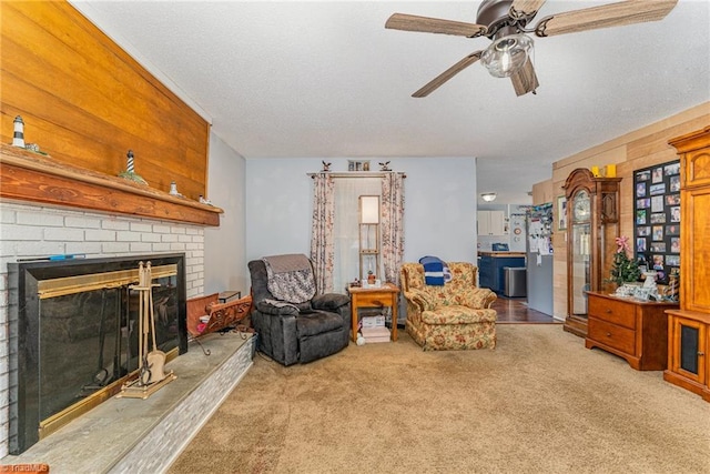 carpeted living area featuring a brick fireplace, a textured ceiling, and ceiling fan