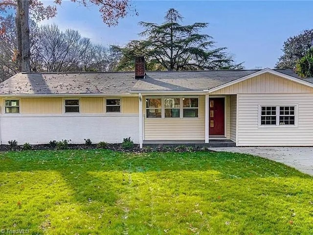 single story home featuring brick siding, a chimney, and a front lawn