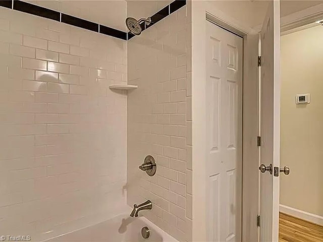 full bath with baseboards and shower / washtub combination