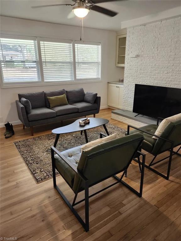 living area with baseboards, a ceiling fan, and light wood-style flooring