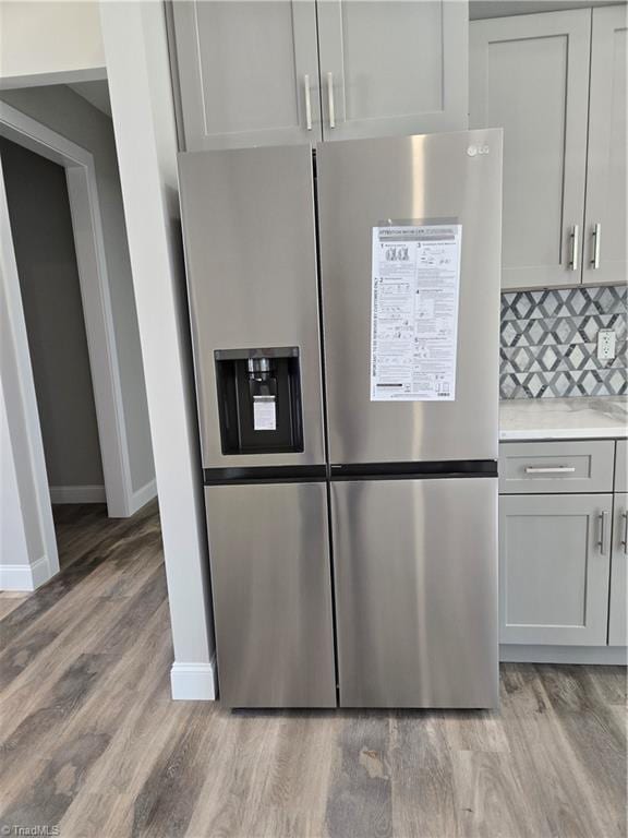 317 Styers Rd, Winston-Salem, NC 27105 - details with decorative backsplash, baseboards, light wood-type flooring, light countertops, and stainless steel fridge with ice dispenser