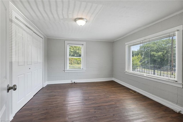 unfurnished bedroom with dark wood-type flooring, crown molding, and a closet