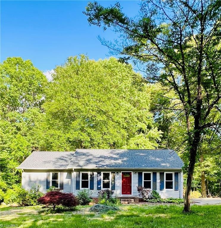 single story home with a view of trees and a front lawn