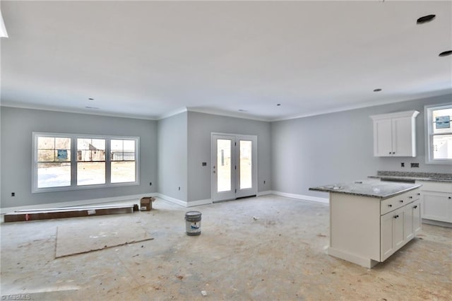 kitchen featuring white cabinetry, a healthy amount of sunlight, a center island, and light stone countertops