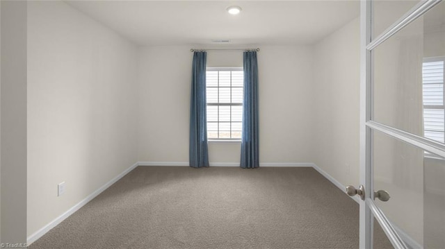 carpeted spare room featuring baseboards