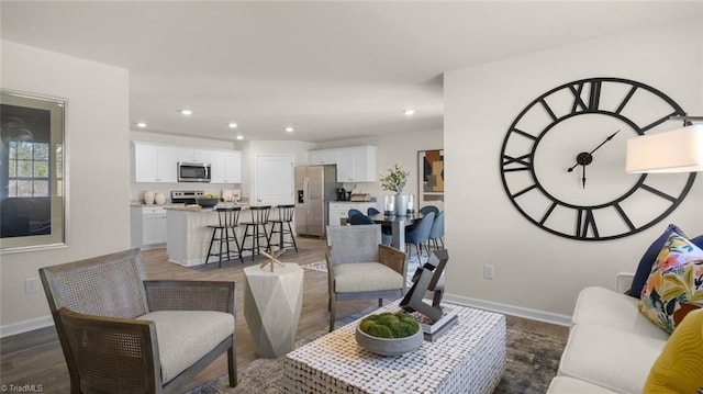 living area with baseboards, wood finished floors, and recessed lighting