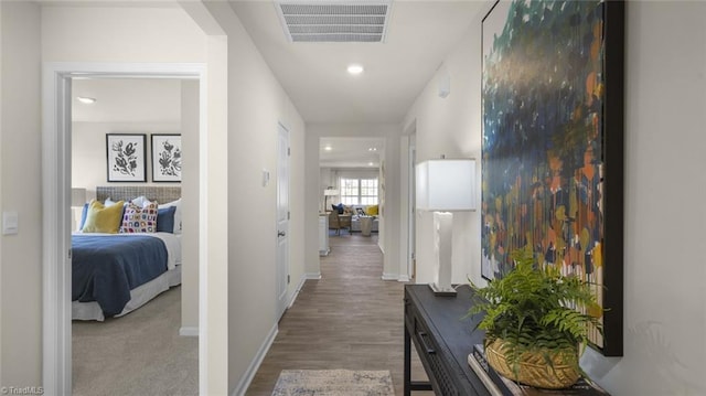 hallway with baseboards, wood finished floors, visible vents, and recessed lighting