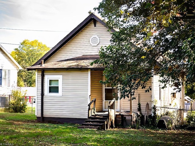 rear view of house featuring central air condition unit and a lawn