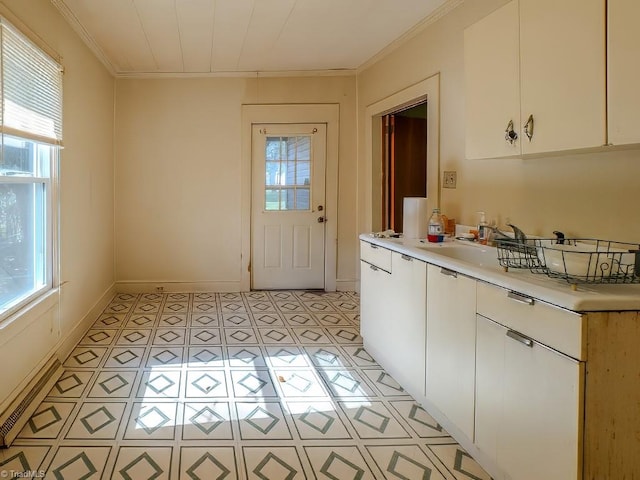 kitchen with white cabinetry, crown molding, light tile patterned floors, and sink