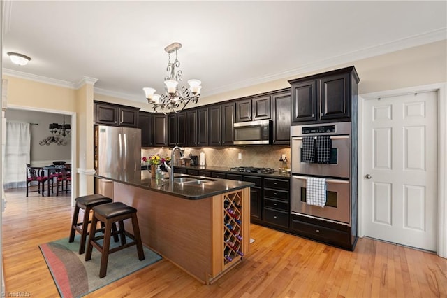 kitchen featuring stainless steel appliances, a sink, a chandelier, a breakfast bar area, and backsplash