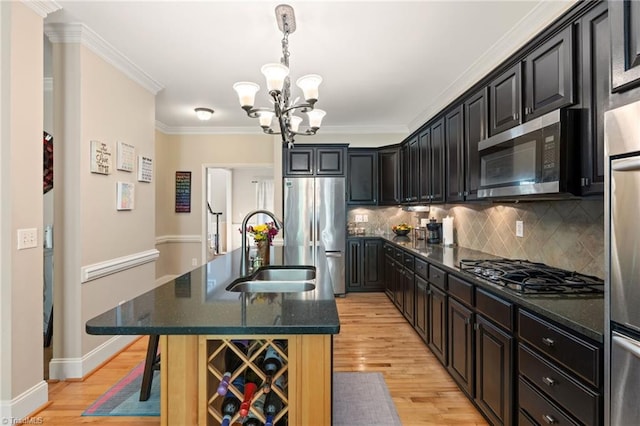 kitchen with stainless steel appliances, a sink, a chandelier, light wood-type flooring, and a center island with sink
